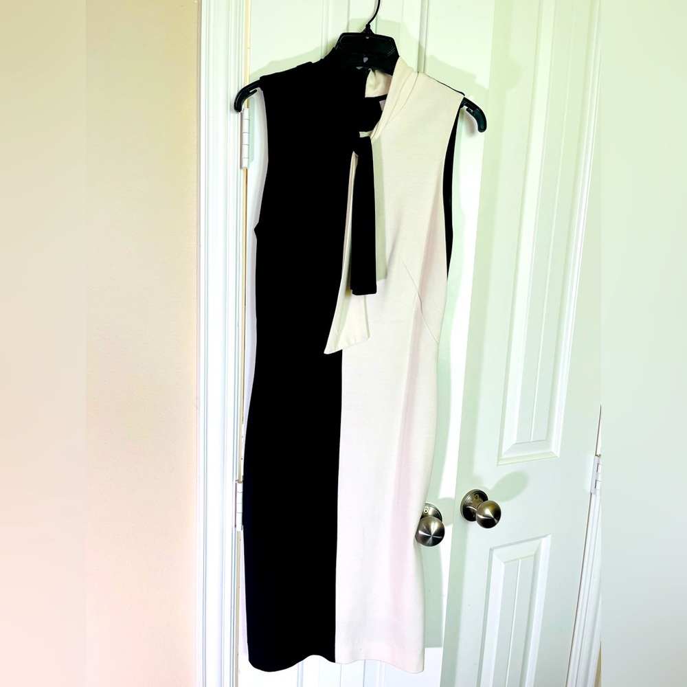 Cache black & white sleeveless dress with tie accessory at the neck.